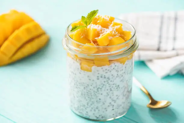 Tasty chia pudding with mango in jar on turquoise background. Healthy food, rich in Omega 3 diet vegetarian food
