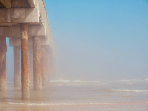 istock Beach pier stretching out into ocean fog 1174874029