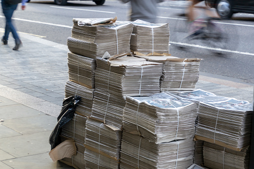 Concept of recycling waste paper. Huge bundles of newspapers lying on the street of a big city.