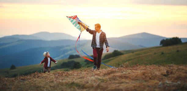 lycklig familj far och barn son lansera kite på ängen - flying kite bildbanksfoton och bilder