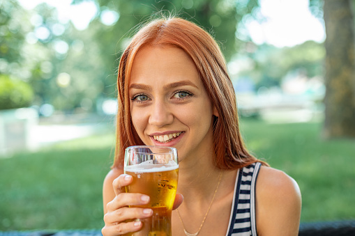 Beautiful Smiling Cute Red-hair Women Drinking Beer in nature, public, outdoor, summer