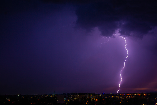 Lightning strikes storm over city purple light