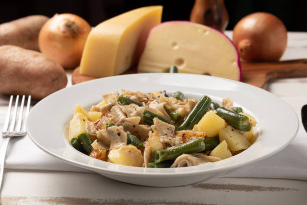 pizzoccheri alla valtellinese casero;  una pasta tradicional de tagliatelle corta típica de la provincia de valtellina, en el norte de italia. placa blanca sobre fondo blanco de madera. luz suave - pizzoccheri homemade tagliatelle italy fotografías e imágenes de stock