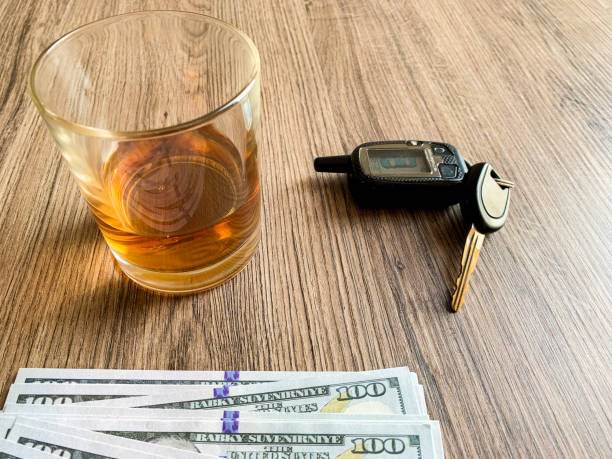istock Drunk driving concept. Glass with whiskey and car key on the table. 1174881624