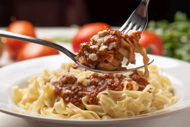 паста феттуччине болоньезе с томатным соусом в белой тарелке на деревенском деревянном столе, мягкий свет - dishware pasta tagliatelle beef стоковые фото и изображения