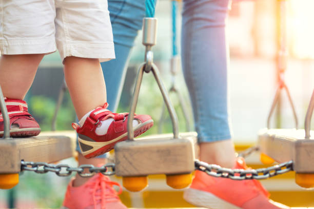 Young adult mother with little cute toddler child having fun enjoying leisure games at outdoor playground on bright sunny day. Mom care and support kid making first steps. Children sport activities. madre adulta joven con pequeño niño pequeño lindo divirtiéndose disfrutando de juegos de ocio en el patio de recreo al aire libre en un día soleado brillante. mamá cuidado y apoyo niño haciendo los primeros pasos. actividades deportivas infantiles
