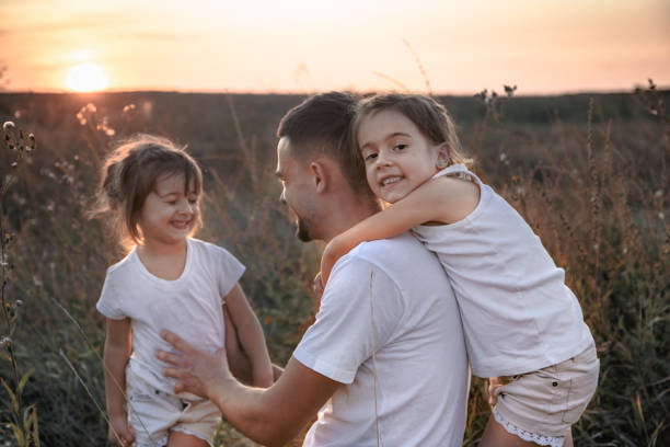 istock Dad and his daughters in the field at sunset . 1174887949