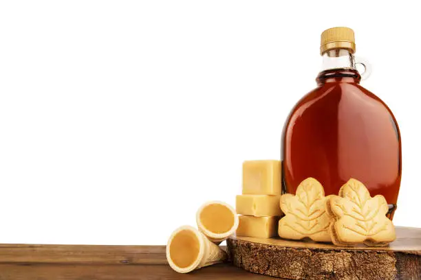 Photo of Maple syrup bottle and maple products on a wooden plank.