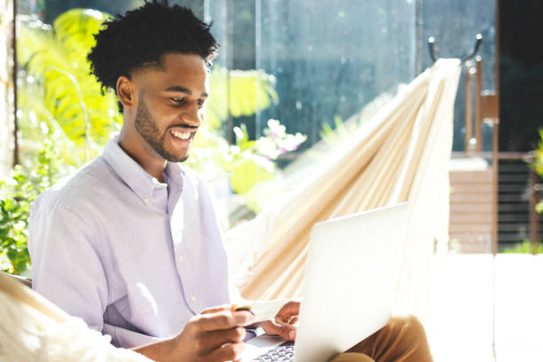 istock Young man using laptop, cell phone and credit card 1174897294