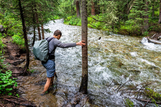 Man crossing river ford on Conundrum Creek Trail in Aspen, Colorado in 2019 summer in forest woods with strong current Man crossing river ford on Conundrum Creek Trail in Aspen, Colorado in 2019 summer in forest woods with strong current ford crossing stock pictures, royalty-free photos & images