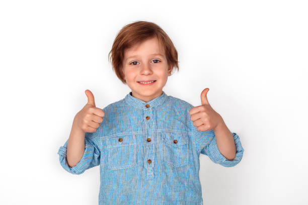 istock Boy studio standing isolated on grey thumbs up looking camera relaxed 1174902715