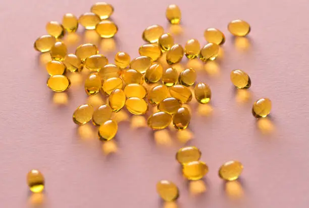 Close up capsules of fish fat oil in the heart shape, omega 3, vitamin Healthy food diet. Nutritional supplement