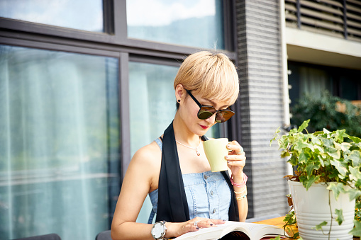 young asian woman enjoying reading and coffee on patio