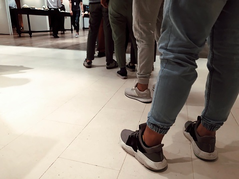 Men standing in row. Close up queue of people waiting in line at restaurant. Copy space