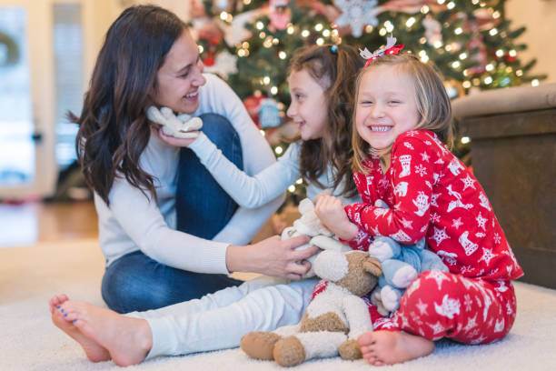 istock Mom laughs with her two daughters in front of the Christmas tree 1174910380