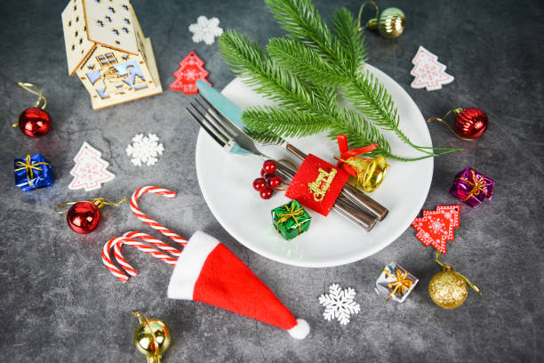 istock Christmas table place setting decoration with gift box ball candy cane in santa claus hat fork and knife plate Xmas New Year food lunch festive Christmas dinner holidays background themed party 1174914533