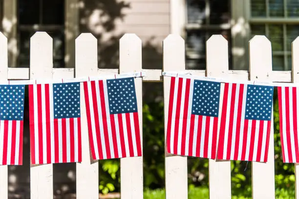 Patriotic American flags hanging decorations on white picket fence in Aspen, Colorado near Independence Day July 4th celebration