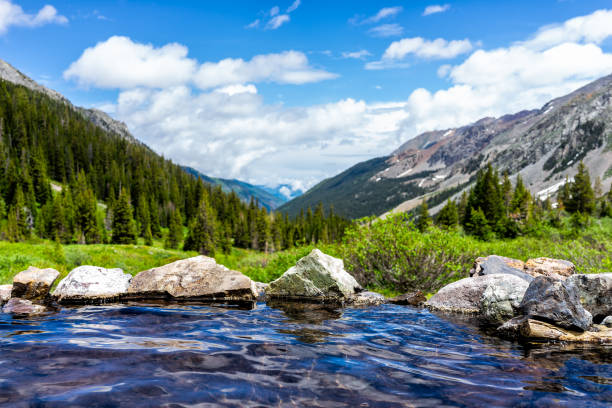 piscine bleue de sources chaudes sur le sentier de ruisseau de conundrum à aspen, colorado en 2019 été avec des pierres de roches et vue de vallée avec personne - hot spring photos et images de collection