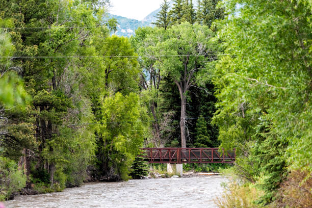 Photo of Highway 133 in Redstone, Colorado during summer with red bridge on Crystal river by trees