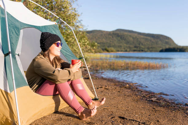 istock Young Women drinking Coffee by the Lake in Camping 1174922064