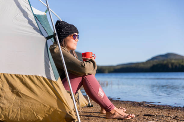 istock Young Women drinking Coffee by the Lake in Camping 1174922207