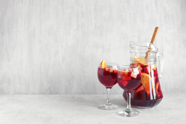 Red wine sangria Red wine sangria or punch with fruits and ice in glasses and pitcher. Homemade refreshing fruit sangria on white background, copy space. sangria stock pictures, royalty-free photos & images