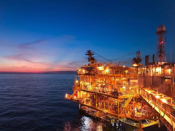 Offshore construction platform for exploration and production oil and gas with bridge in evening time for power energy of the world concept stock photo