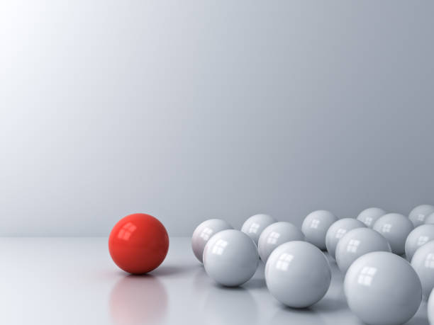 istock Leadership concept one red sphere leading whites over white room background with reflections and shadows 1174931894