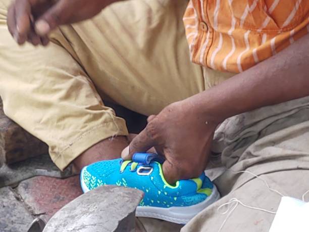 istock Cobbler stitching shoes with a knife and a thread 1174932071
