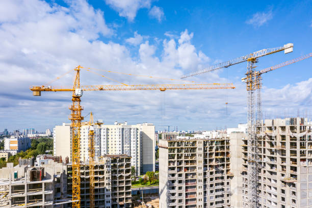 istock industrial cranes at construction site against blue sky background. development of new residential area 1174932281