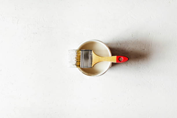 istock Construction brush with red handle on paint jar on painted plywood. 1174933279