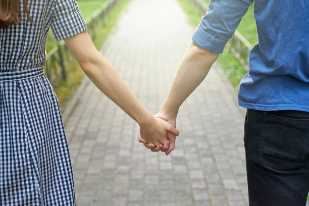 istock Couple holding hands while walking in the park closeup 1174935286