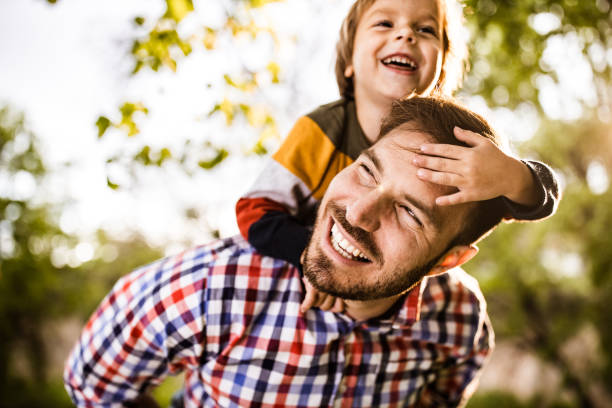 istock Happy single father piggybacking his small son in the park. 1174936175
