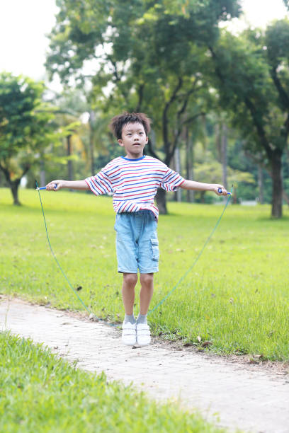 istock Little boy jumping rope on grass 1174939041