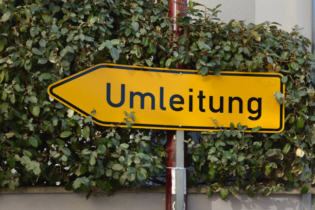segnale stradale freccia tedesco giallo che punta a sinistra e dice "deviazione del percorso" - redirecting foto e immagini stock