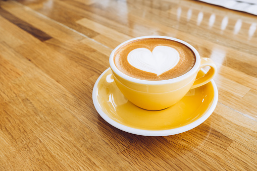 hot cappuccino coffee cup on wooden tray with heart latte art on wood table at cafe,Banner size food and drink concept.