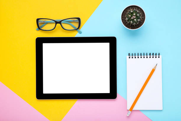 istock Tablet computer with office supplies on colorful paper background 1174942489