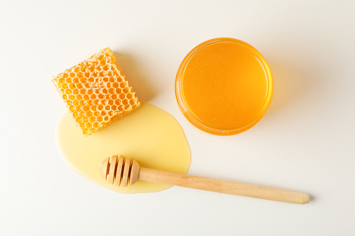 Honeycomb, dipper and jar with honey on white background, top view