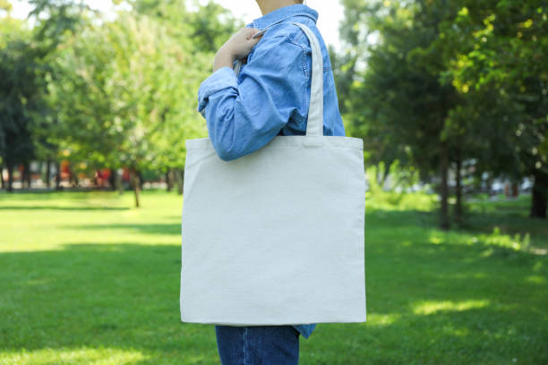 istock Young woman holding tote bag against greenery background, empty space 1174942664