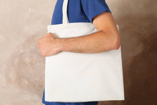 istock Young man holding tote bag against brown background, empty space 1174942678