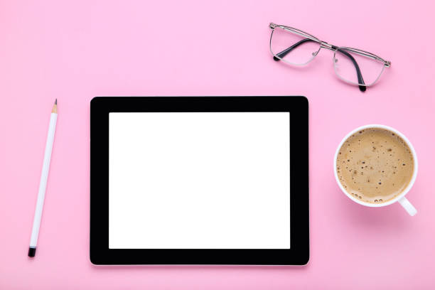 istock Tablet computer with glasses and cup of coffee on pink background 1174942795