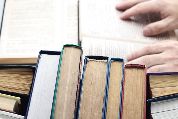 istock Student reading book in library. Studying at college library, books on the table. Study, school and education concept 1174942835