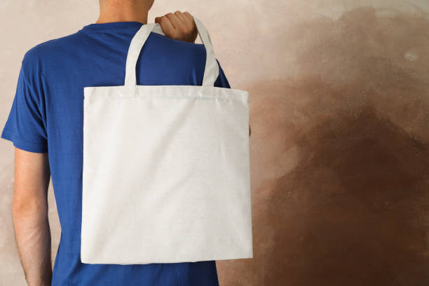 istock Young man holding tote bag against brown background, empty space 1174942853