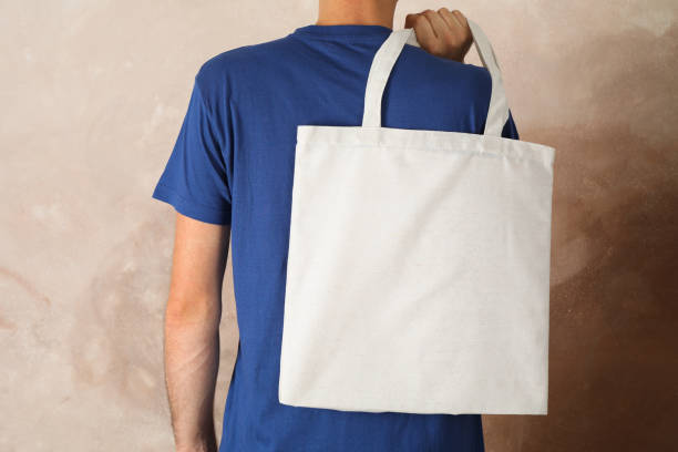 istock Young man holding tote bag against brown background, empty space 1174942866