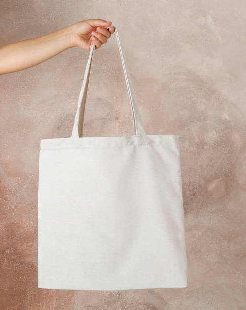 istock Female hand holding tote bag against brown background, empty space 1174942908