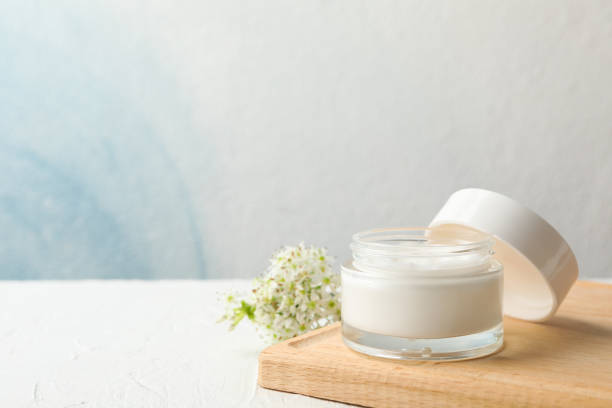 istock Jar with cream, allium flowers and board on white background, copy space 1174943470