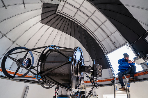 Astronomer technician in observatory telescope dome doing shutter maintenance tasks