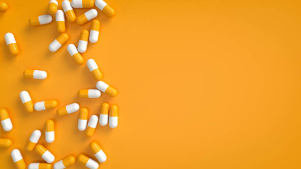 цветные таблетки на оранжевом фоне - painkiller pill capsule birth control pill стоковые фото и изображения