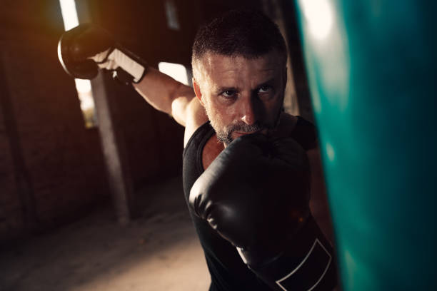 istock Male boxer punching a boxing bag in warehouse. 1174946553