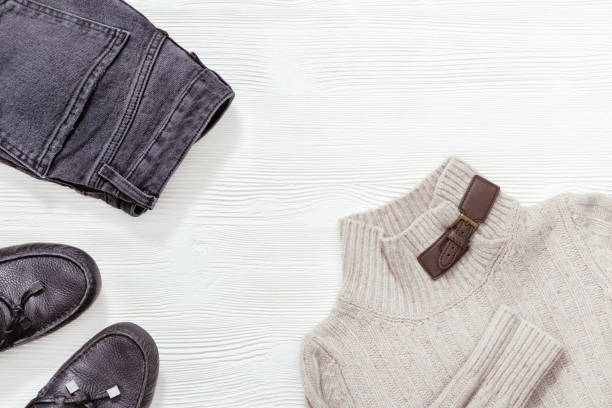 istock Winter, fall female clothing. Black leather moccasins, dark jeans and light grey pullover on white wood background with copy space. Flat lay. 1174947103